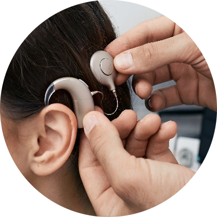 best Audiologists in dubai fitting a hearing aid in a female patient’s ear at a leading audiology clinic in Dubai